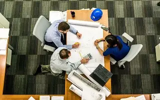 Three people working at table looking at drawings