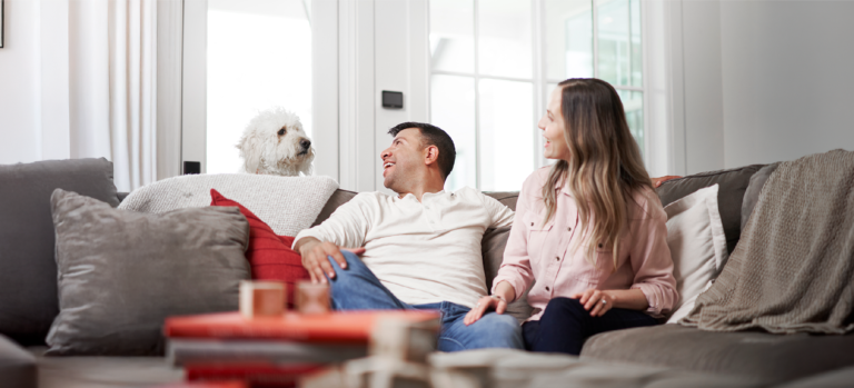 Younger homeowners on sofa with their dog